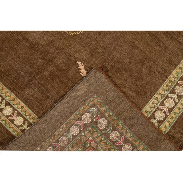 Beautiful Modern hand-knotted wool rug with a brown field. This Revival Collection rug has blue, pink, yellow, and green...