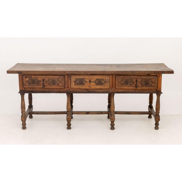 Spanish Baroque-Style Walnut Console Table, with three drawers on eight turned wood legs conjoined by center stretcher....