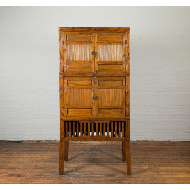 A Chinese vintage wood and bamboo cabinet from the mid 20th century, with double doors and openwork apron. Created in...