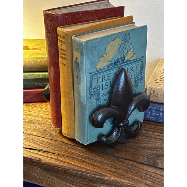 These heavy vintage cast-iron bookends feature a classic fleur-de-lis design. Finished in a rich matte black, these sturdy...