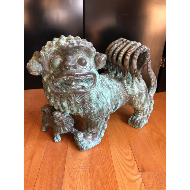 Pair of last bronze Chinese guardian foo dog lions consisting of male lion with hanging ball referred to as "Flower of...
