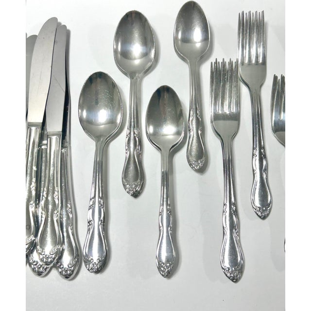 A complete 48-piece vintage Rogers stainless steel flatware set featuring a softly sculpted mid-century floral pattern....