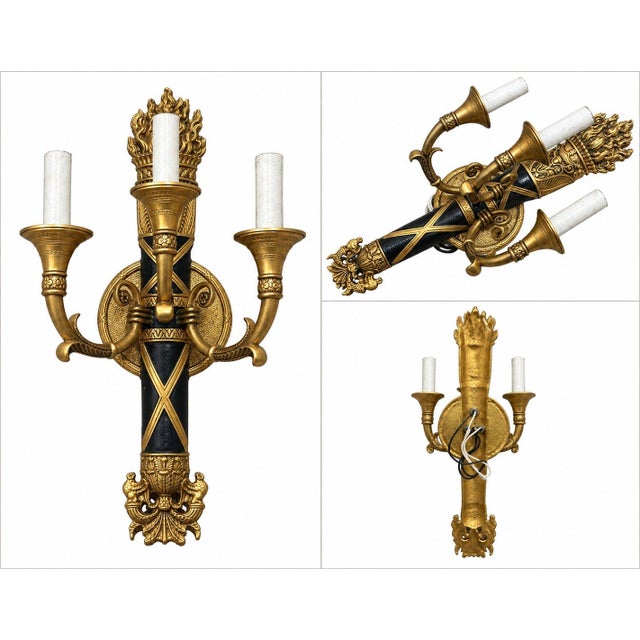 Elegant vintage 3-light wall sconce featuring an ornate neoclassical design with a striking combination of antique gold-...