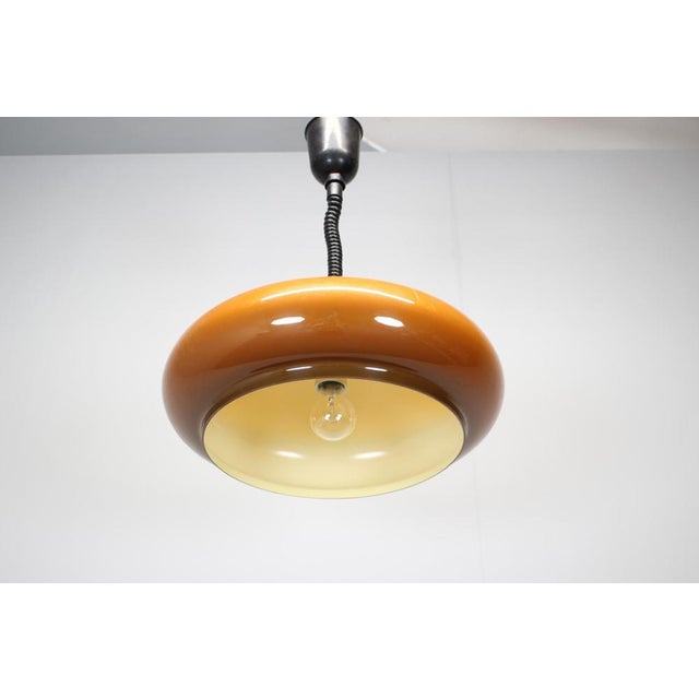 A Mid-Century modern adjustable glass pendant lamp produced in Europe during the 1970s. The lamp features a classic pull-...