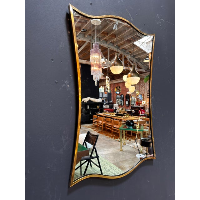 "A captivating vintage Italian sculptural brass wall mirror crafted in Italy during the 1970s, showcasing intricate design...
