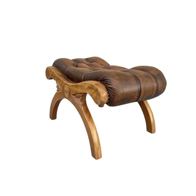 A very elegant Chesterfield footstool from the 1960s, made from expertly carved beech wood with authentic brown leather...