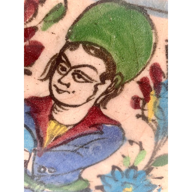 Intriguing antique Persian tile hand painted in deep blues, greens and reds. In the position of the musician you see the...