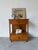 A clean and functional 1960s Mid-Century Modern nightstand featuring warm wood tones and a minimalist open-frame design....