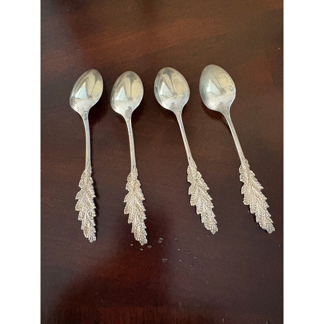 Beautiful antique set of four sterling silver teaspoons featuring an elegant grape-and-vine design. Each spoon is marked...