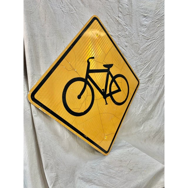 This Vintage Reflective Road Sign depicts a black bicycle with a yellow background. Once used as a street sign to inform...