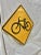 This Vintage Reflective Road Sign depicts a black bicycle with a yellow background. Once used as a street sign to inform...