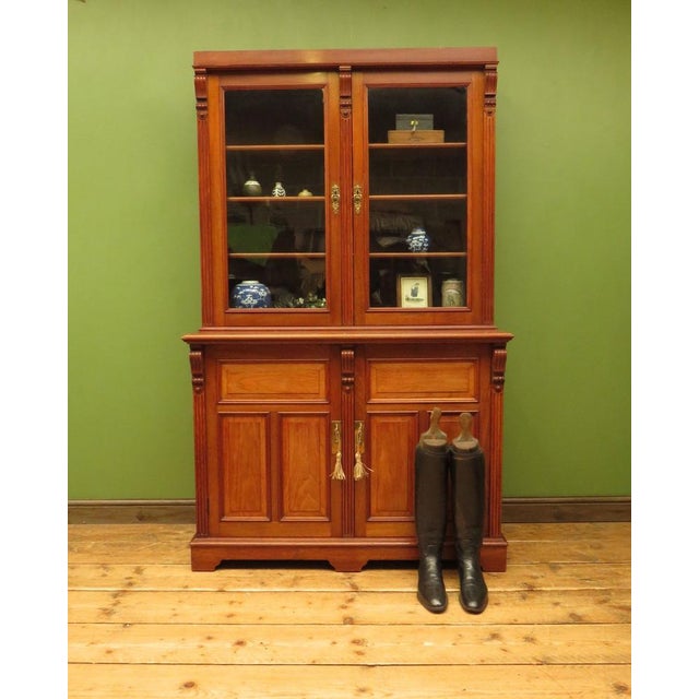 This is a handsome antique book cabinet which dates to the early 20th century. It is an elegant and substantial piece...