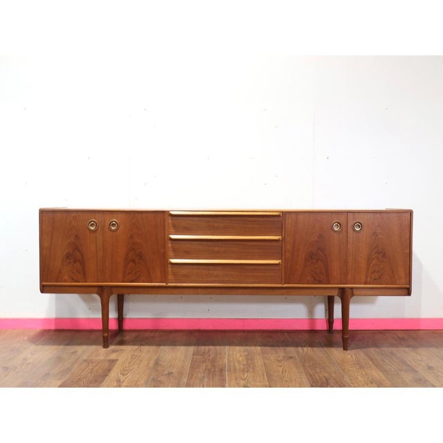 This elegant Mid-Century Modern teak sideboard in the style of Scottish furniture maker McIntosh exemplifies the refined...