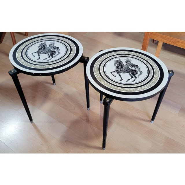 A pair of side or end tables in the manner of Piero Fornasetti with a Greek warrior on a horse. Formica tops with wooden...