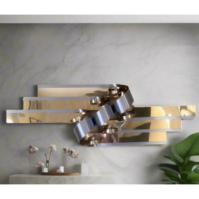 Large, wide wall sculpture by C Jere has long strips of brass and chrome twisted in the center.