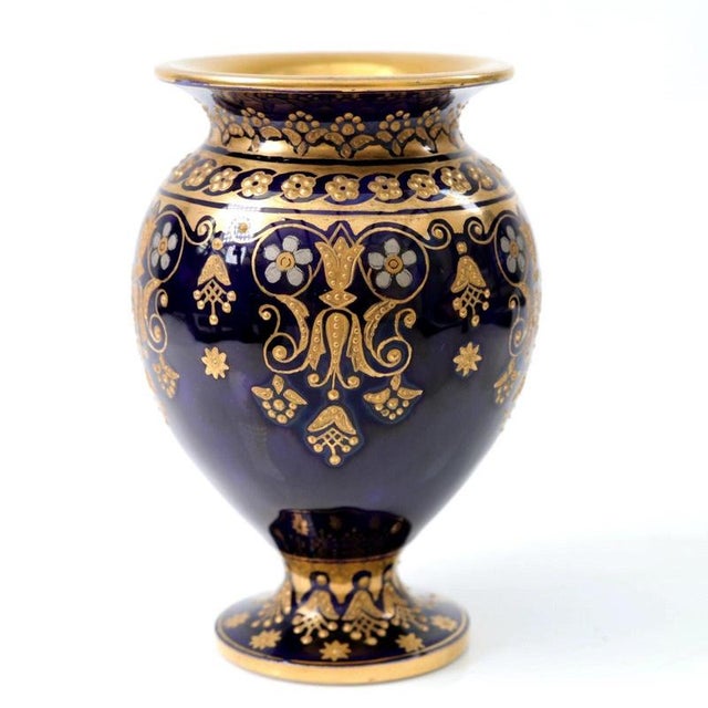 Raised gilt scrollwork and delicate white enamel jewelling encircle the deep cobalt blue ground of this Coalport porcelain...