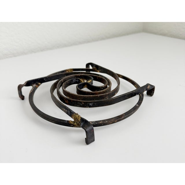 Rustic steel dimensional trivet or wall sculpture with abstract swirl pattern. Four feet lift the piece off the surface....