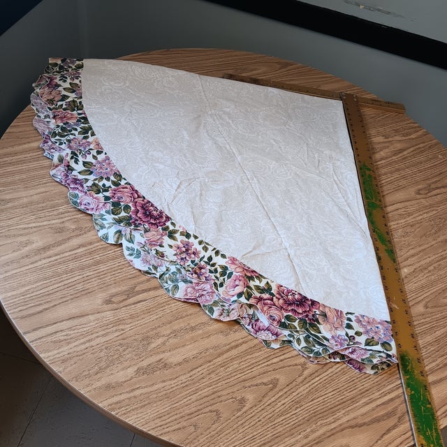 Vintage table cover, 1990s. Pretty leaf pattern in beige and white with a flowered ruffle. Measures 66" across with the...