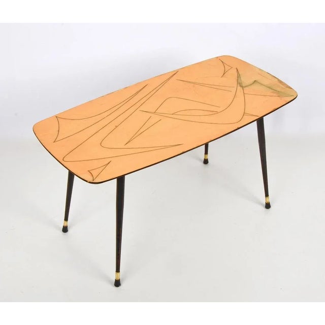 Marvellous mid-century coffee table in drawn wood, brass and black enamelled metal. This table was produced in Italy...