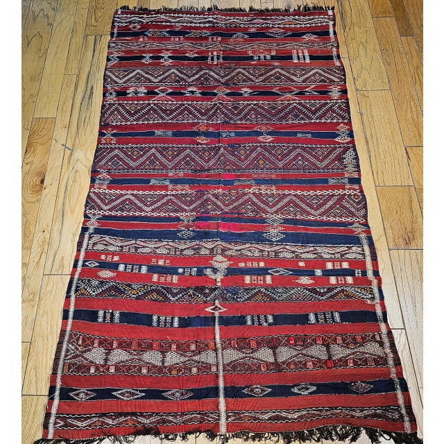 This vintage Moroccan tribal Kilim from the Atlas Mountains, dating to the mid-1900s, is a striking example of North...