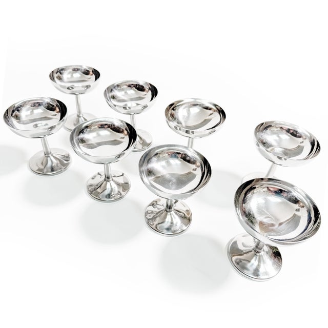 Dazzle your guests with this striking vintage set of eight polished stainless steel stemmed coupes featuring the...
