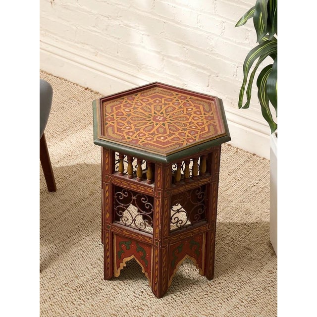 A richly detailed vintage Moroccan side table featuring a hexagonal silhouette and an intricate hand-painted geometric...