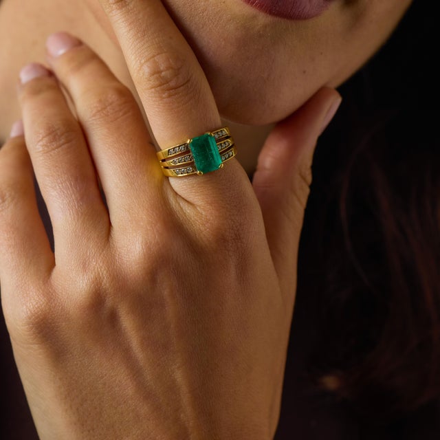 This elegant vintage emerald and diamond ring is a refined jewel from the 1980’s, crafted in warm 18k yellow gold with a...