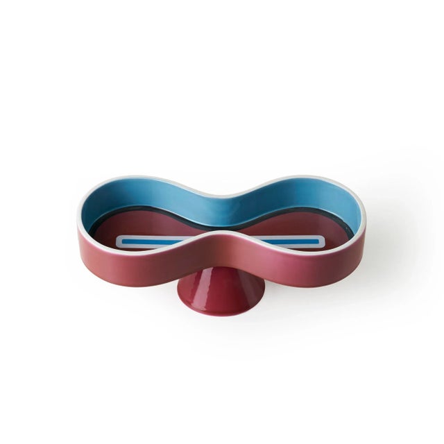 This bowl from the Symbolik collection was cast in white earth and is enameled in bright burgundy and turquoise with...