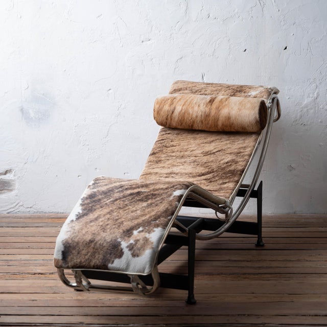 An LC4 style chaise lounge chair in cowhide. 64 inches wide by 23 inches deep by 28 inches tall