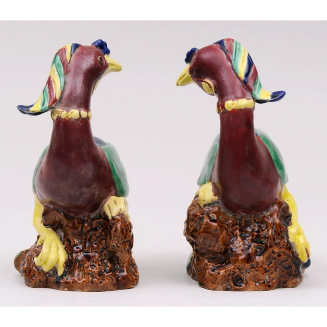 Pair of Chinese colorful polychrome glazed biscuit models of phoenix birds perched on rockwork decorated in yellow, green,...