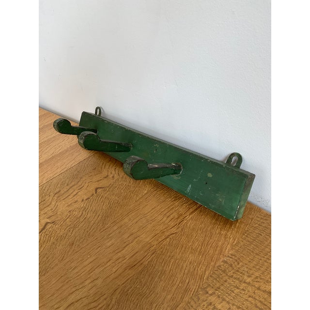 Featuring a beautifully aged, distressed green painted finish, this original wooden coat/hat rack offers immense character...