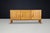 A powerful French Modernist sideboard by Maison Regain, carved from solid elm with bold architectural doors and warm...