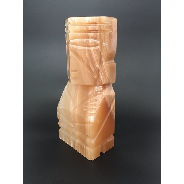 A vintage hand carved Aztec figure made from onyx stone in a warm amber-yellow shade. The natural variations in the stone...