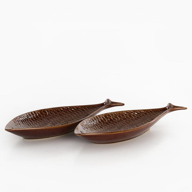 A charming pair of ceramic fish-shaped serving dishes designed by celebrated Swedish designer Stig Lindberg for...