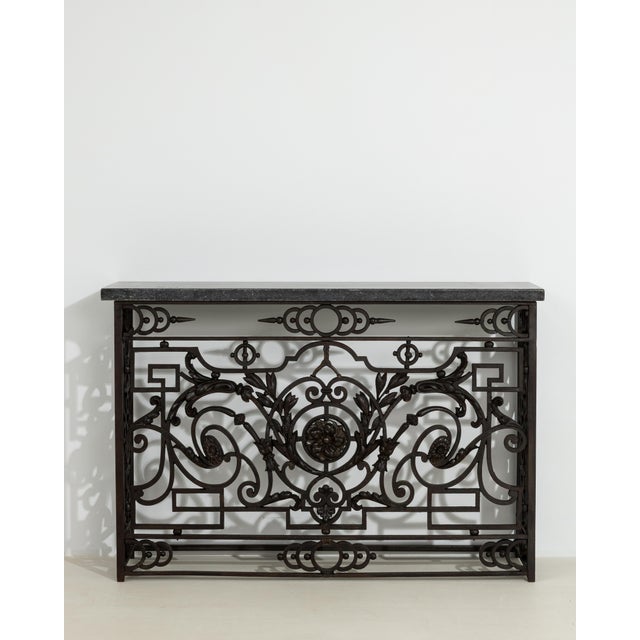 A neoclassical console table with a wrought iron frame and bluestone top. The design features clean lines with subtle...
