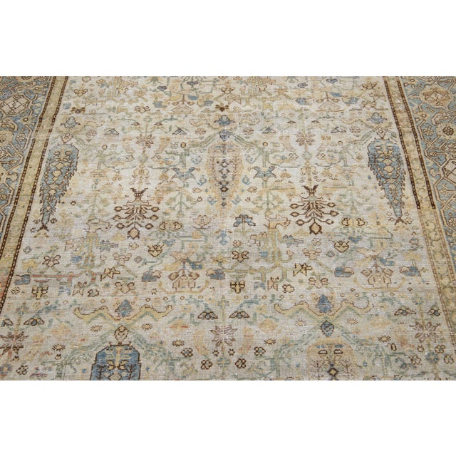 Beautiful antique Malayer hand-knotted wool rug with a beige color field. This Persian rug has beige, blue, and rust...