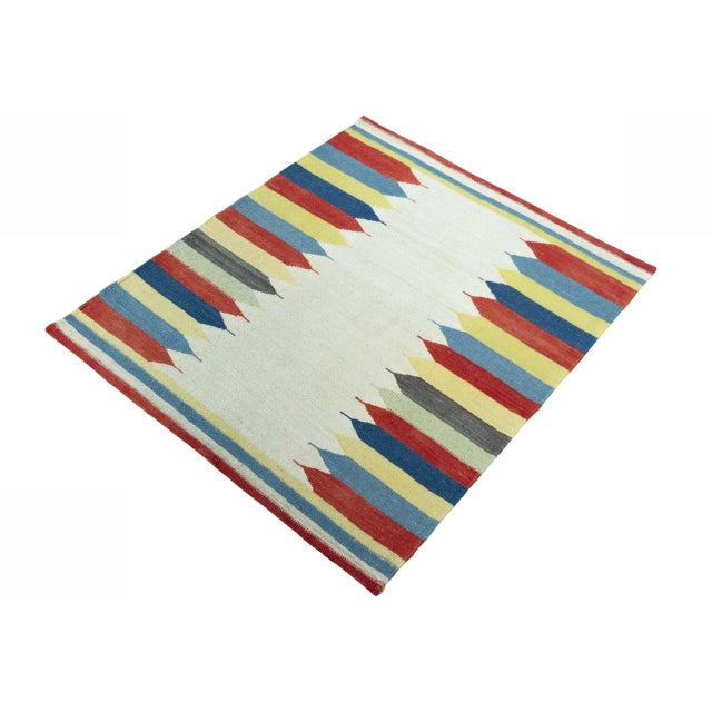 This handwoven Fars kilim impresses with its unusual design: Intensely colorful, arrow-like shapes in red, blue, yellow,...