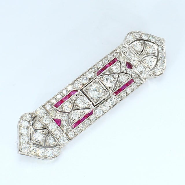 This rectangular brooch features a central old European cut diamond, surrounded by intricate patterns of white diamonds....
