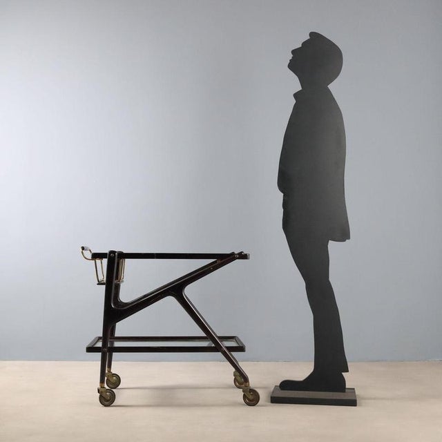 Italian-made 1950s trolley featuring a functional design and elegant ebony-stained wood structure. The double glass shelf...