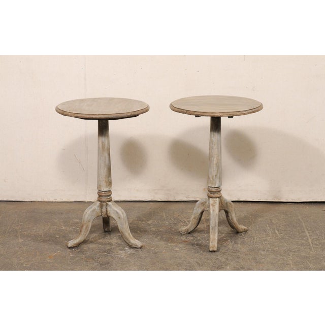 An American-made pair of painted, round pedestal side tables. These vintage smaller-sized tables each feature a `17.75...