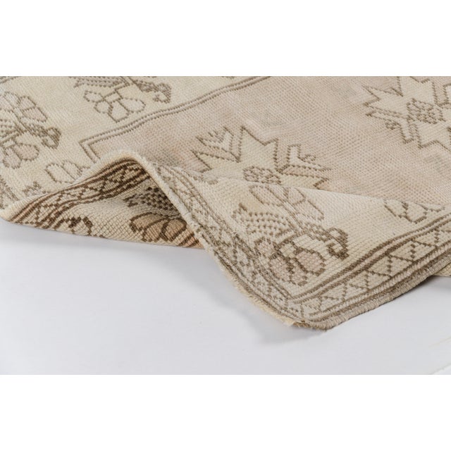 This is a vintage Turkish Oushak rug from the Mid 20th Century. The piece was hand-knotted.