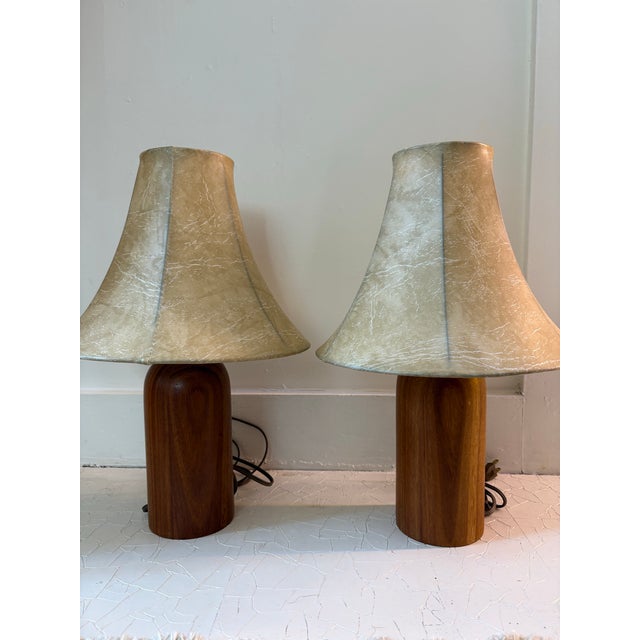 Pair of 1950s era turned teak table lamps. Paired with original bell shaped vinyl shades. Diminutive size, casts a soft...
