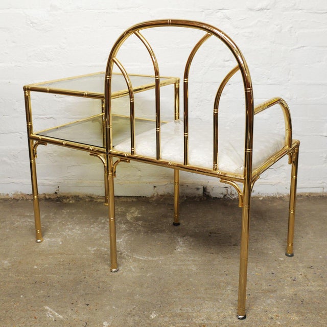 A hollywood regency brass telephone seat and side table. This piece is attributed to the mentioned designer/maker. It has...