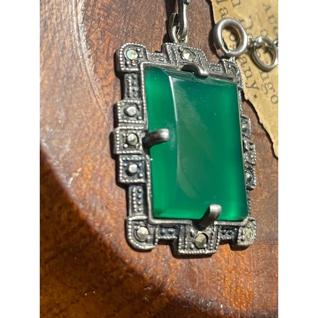 This Art Deco necklace is a stunning display of period elegance, balancing structured geometric filigree with the lush,...