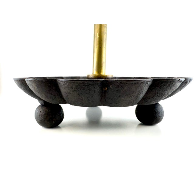 A vintage fireplace tool stand featuring a solid brass center post with four gracefully scrolled tool holders rising from...