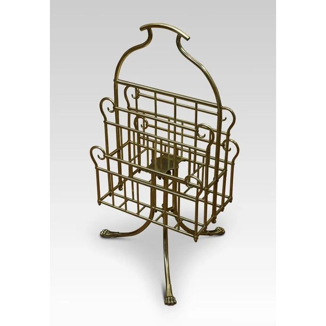 Brass music / magazine rack with scrolled and railed divisions, on three out splayed supports termanating in paw feet....