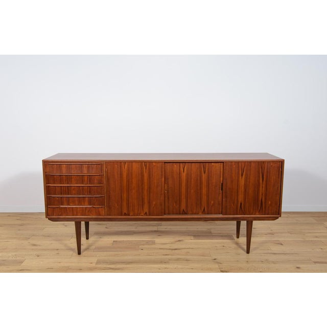 Sideboard made in the 1960s in Denmark. Sideboard consists of three sliding doors and five drawers, inside there are...