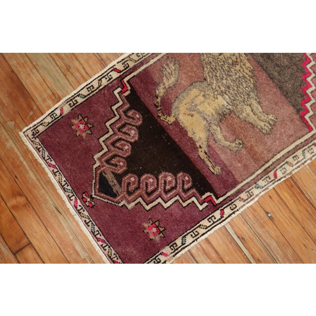 A mid-20th century authentic Turkish rug depicting a lion on a striated purple ground. Measures: 1'10" x 3'2”.