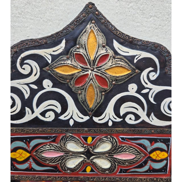 Vintage Moroccan hand‑painted mirror featuring an ornate arched frame adorned with colorful floral and geometric motifs....