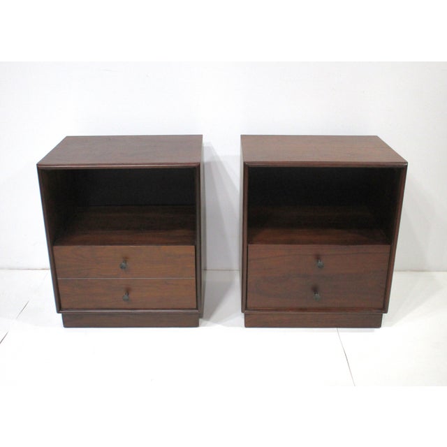 A pair of dark walnut nightstands with open top storage cubie and a large single lower drawer with black metal pulls all...